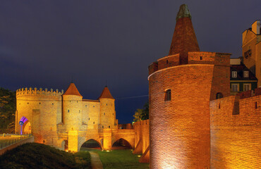Illuminated medieval Warsaw Barbican in Old Town, Warsaw, Poland, captured at night with brick walls and towers