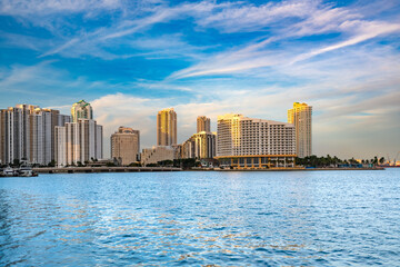 A view of the exclusive island community of Brickell Key, with its luxury buildings illuminated against the evening sky.