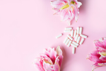 White capsules with pink lily on pastel background