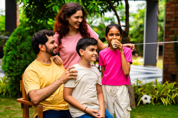 Parents and kids enjoying playful moment using string telephone in backyard garden