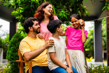 Parents and kids enjoying playful moment using string telephone in backyard garden