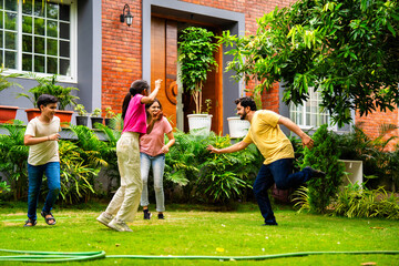 Indian family playing Langdi or one-leg hop game in garden, enjoying energetic outdoor fun