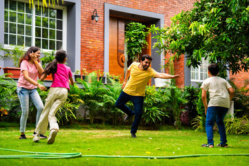 Indian family playing Langdi or one-leg hop game in garden, enjoying energetic outdoor fun