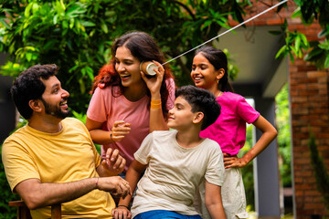 Parents and kids enjoying playful moment using string telephone in backyard garden