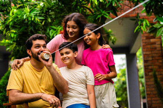 Parents and kids enjoying playful moment using string telephone in backyard garden
