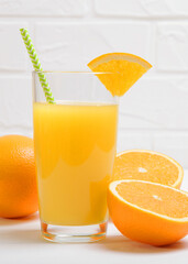 Orange juice in a glass, oranges and orange slices on the table.. Vertical photo format