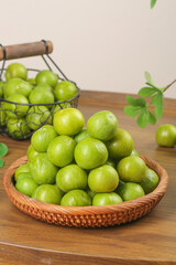 Fresh Green Plums in Wicker Basket on Wood Table - Healthy Organic Fruit Display