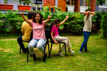 Indian parents and children bond through musical chair fun in backyard garden setting