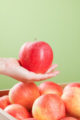 Fresh Red Apple in Hand Above Crate of Ripe Apples - Healthy Fruit Selection