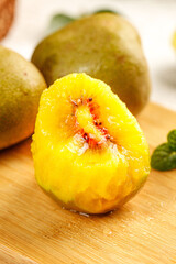 Fresh Yellow Kiwi Fruit Cut in Half Showing Golden Flesh on Wooden Board