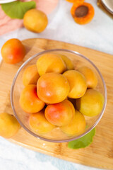 Fresh Small Xinjiang Apricots in Glass Bowl on Wooden Board with Bright Light Background
