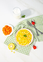 Fresh Golden Corn Kernels in Bowl with Milk and Vegetables on Green Checkered Tablecloth