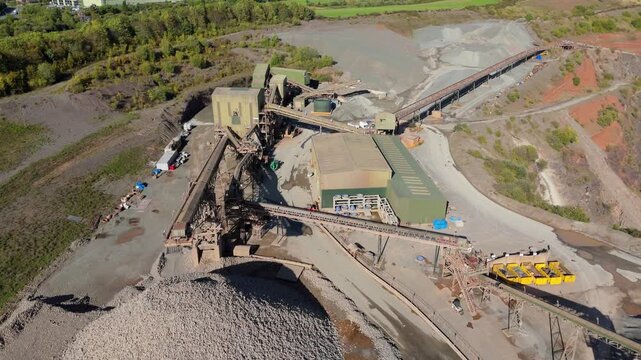 Aerial drone view of huge quarry mining operational facility, extracting rare earth minerals, heavy plant machinery and industrial conveyor belts in Coalville England UK sunny 