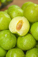 Fresh Sichuan Plums with Water Droplets on Wood Background - One Cut Half Showing Pit