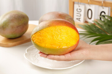 Fresh Ripe Mango Half in Hand Showing Juicy Orange Flesh with Tropical Setting