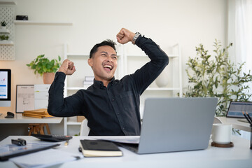 Young businessman celebrating achievement in workplace.