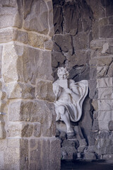 Ancient stone sculpture representing time with hourglass and scythe in grotto niche