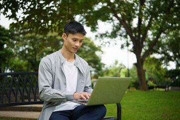 Fototapeta premium Man working remotely on laptop, digital nomad lifestyle in green outdoor workspace.