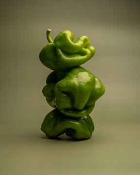 Naklejki Artistic abstract still life of green bell peppers with surreal organic shapes, sculptural vegetable stack, creative minimal food photography, concept, healthy eating, balancing structure
