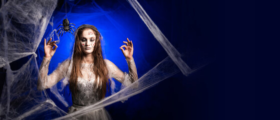 Calm creepy woman with horrible scary Halloween zombie makeup in white dress meditating making yoga...