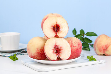 Fresh Golden Peaches Cut in Half on White Plate with Mint Leaves and Tea Cup