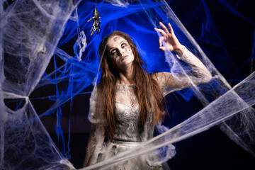 Sinister creepy woman with horrible scary Halloween zombie makeup in white dress showing ok gesture...