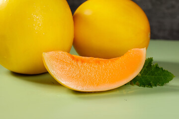 Fresh Honeydew Melons from Gansu Shaanxi China with Orange Flesh Slice and Mint Leaf on Yellow Background