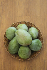 Fresh Green Mangoes from Panzhihua Sichuan in Wicker Basket on Wood Table - Tropical Fruit Display