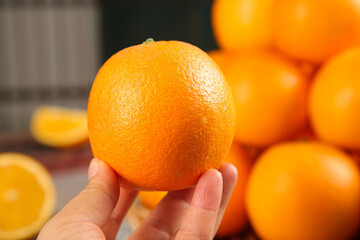 Fresh Orange Held in Hand with Citrus Fruits on Wooden Background - Healthy Summer Food Concept