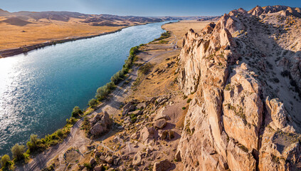 Aerial panoramic view of Ili River flowing through canyons and desert landscape in Kazakhstan at sunset © EdNurg