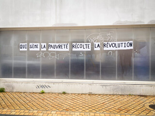 French protest poster stuck on a wall by left wing feminists saying "he who sows poverty reaps revolution"
