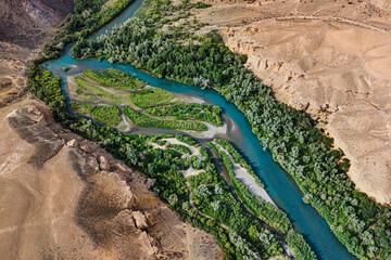 Aerial view of a beautiful river flowing through a canyon, creating a stunning contrast between turquoise water, green vegetation, and arid landscape