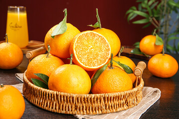 Fresh Orange Citrus Fruits in Wicker Basket with Juice Glass on Wooden Table