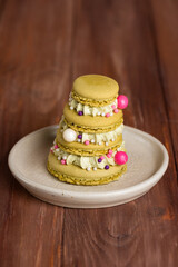 French Christmas tree macaroons in a plate on a wooden table. Merry Christmas and Happy New Year. Vertical orientation.