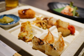 Assorted dishes served on a hotel buffet plate including grilled gyoza dumplings, side dishes, and appetizers, delicious Japanese cuisine in casual dining setting