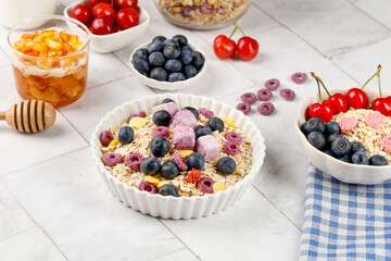 Healthy oat chunks breakfast bowl with fresh blueberries raspberries and plain yogurt with honey and fruit slices