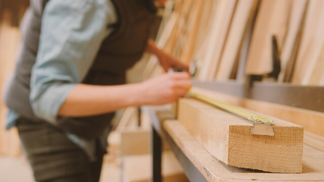 Close Up Of Female Carpenter Working In Woodwork Workshop Measuring Wood For Project