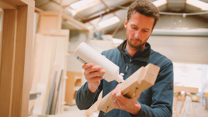 Carpenter In Workshop Joining Wood Together With Glue