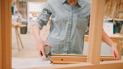 Close Up Of Female Carpenter Working In Woodwork Workshop Making And Measuring Window Frame