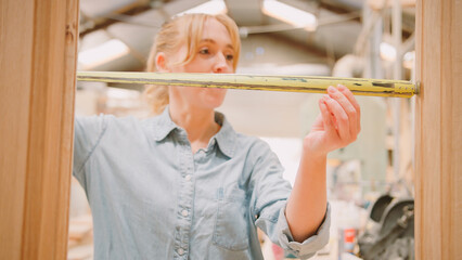 Close Up Of Female Carpenter Working In Woodwork Workshop Making And Measuring Window Frame