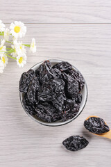 Dried Prunes from Xinjiang in Bowl on White Wood Background with Flowers