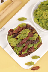Xinjiang Green and Red Raisin Assortment in White Bowls on Wood Background