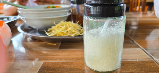Granulated white sugar is placed in clear glass bottle with black plastic cap. The bottle is placed on the dining table for use as a seasoning. It adds sweetness to food. Do not eat exceed 24 g : day.