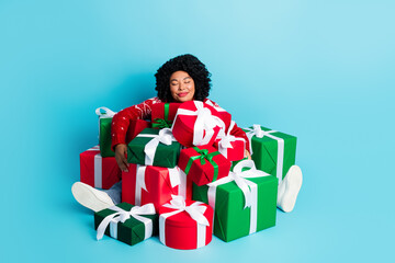 Joyful young woman embracing holiday spirit with festive wrapped presents against a vivid blue background
