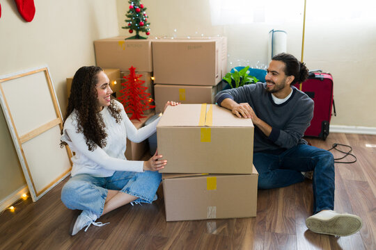 Latin couple unpacking boxes in new home during christmas time