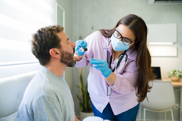 Fototapeta premium Female doctor performing medical checkup at home on male patient