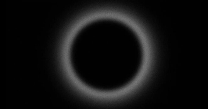 Abstract blurred grainy hole with pulsing halo, looped on black background