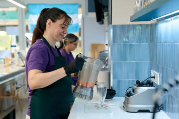 Ice cream shop employee pouring smoothie into glass