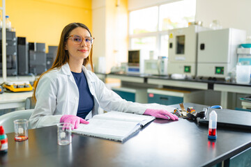 Young female scientist working in laboratory with research notes