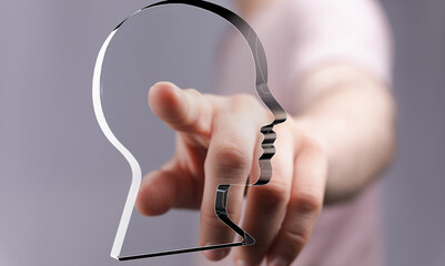 Image depicts a hand pointing at a translucent head profile, symbolizing introspection, self-discovery, or personal identity.